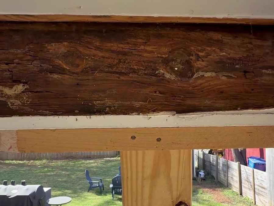 The carport beam with the ceiling opened up, showing rot through the timber, temporarily held by a new post