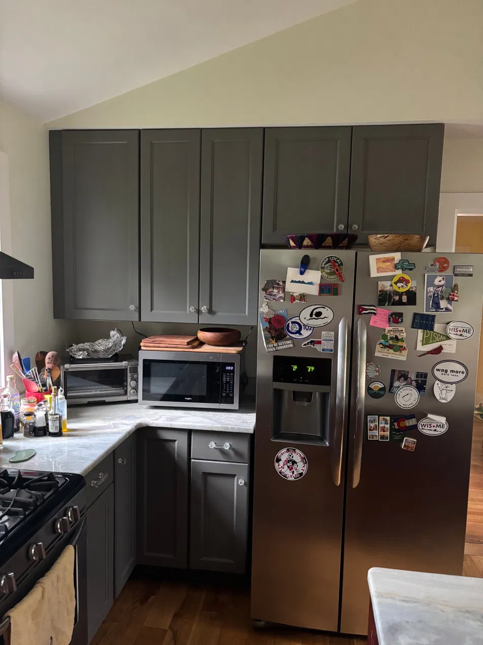 The original kitchen — gray cabinets, light stone tops, and a microwave taking up the corner counter