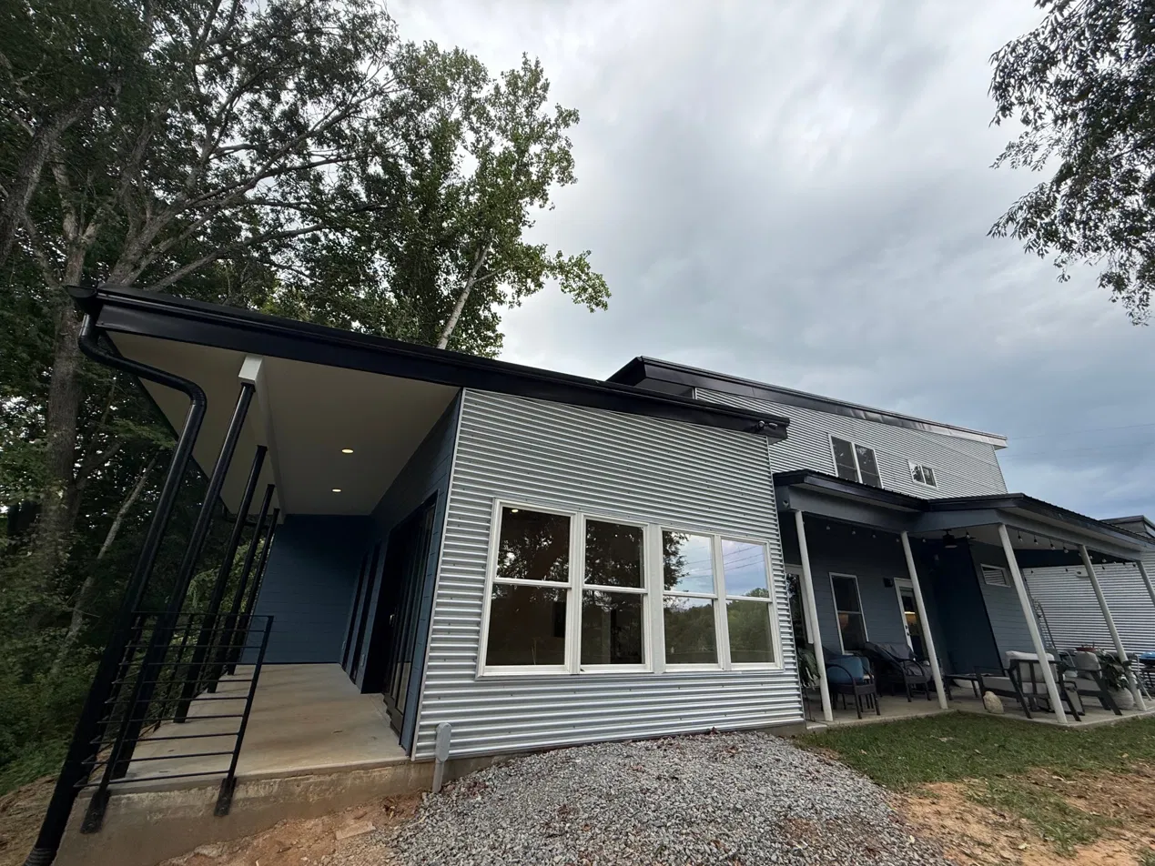 The completed addition — row of windows, stairs to covered porch, siding matched to the existing house