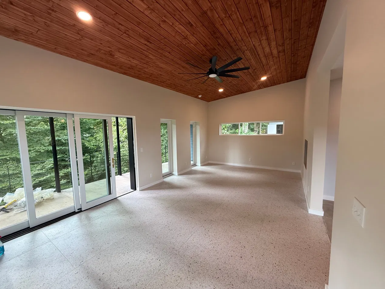 The finished treetop room interior looking toward the slider, one panel open, trees visible through the glass
