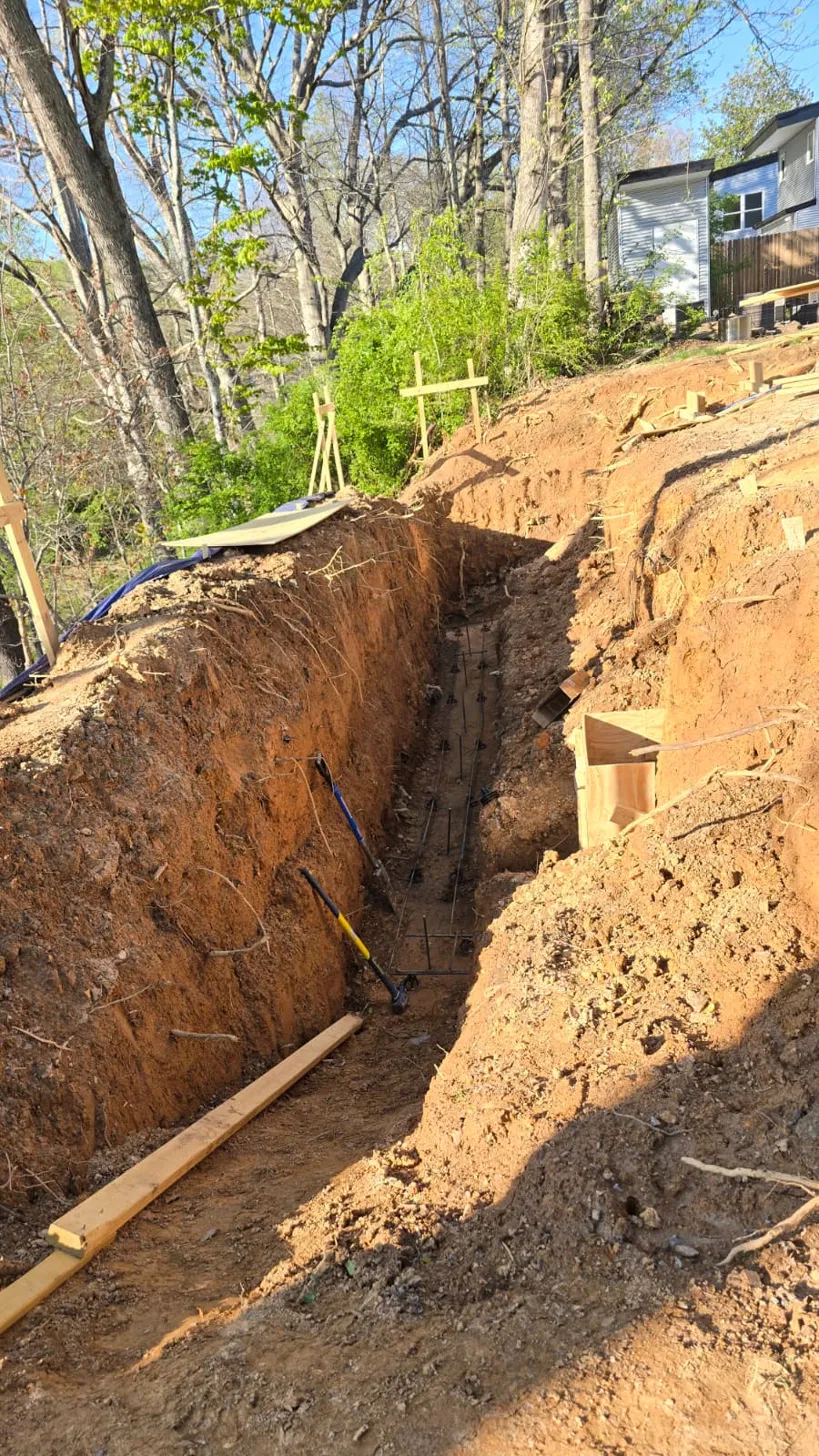 Foundation trench with rebar in wooden forms before the pour, along the hillside