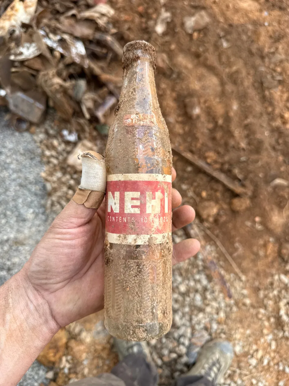 An old Nehi glass soda bottle found in the buried fill during excavation, held in hand